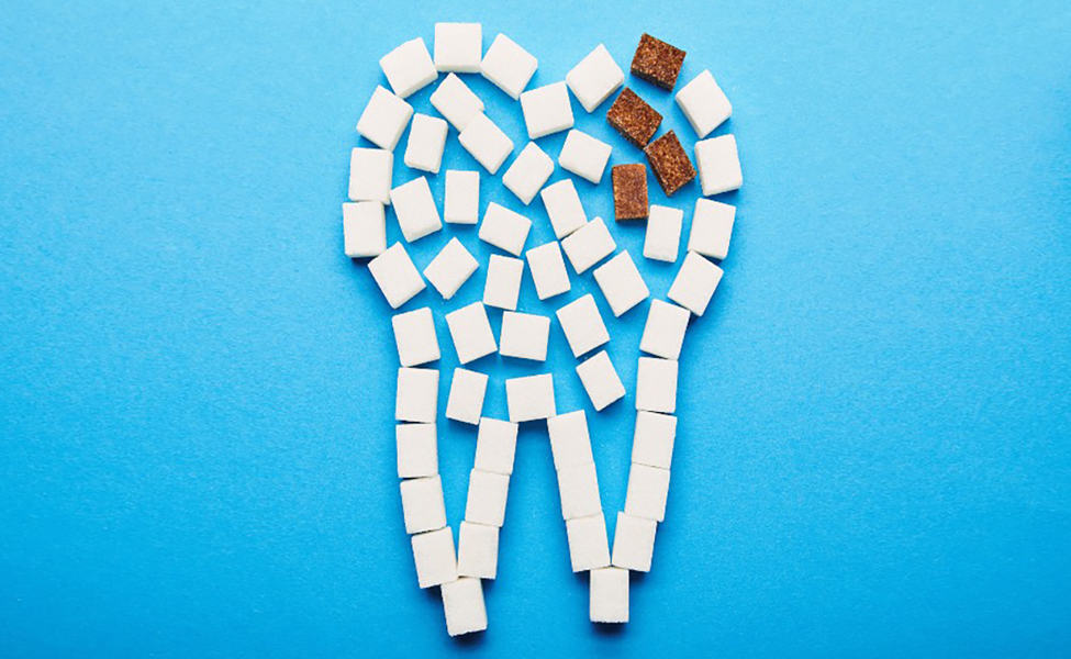 Canva top view of white and brown sugar cubes arranged in tooth sign on blue background dental caries concept