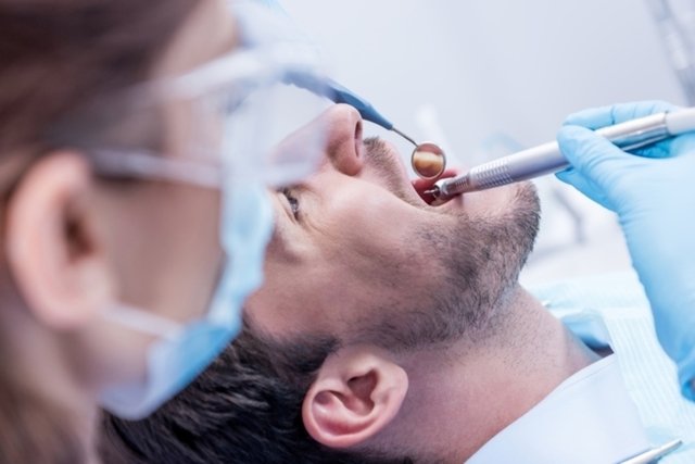 Anginas de ludwing son revisadas por especialista con instrumentos dentales en hombre joven con barba.