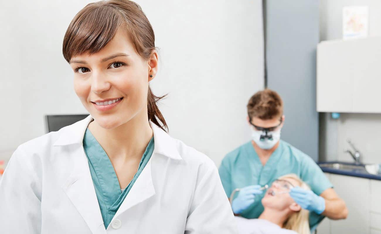 asistente de dentista sonriendo con dentista y paciente detras periodoncia e implantes monterrey