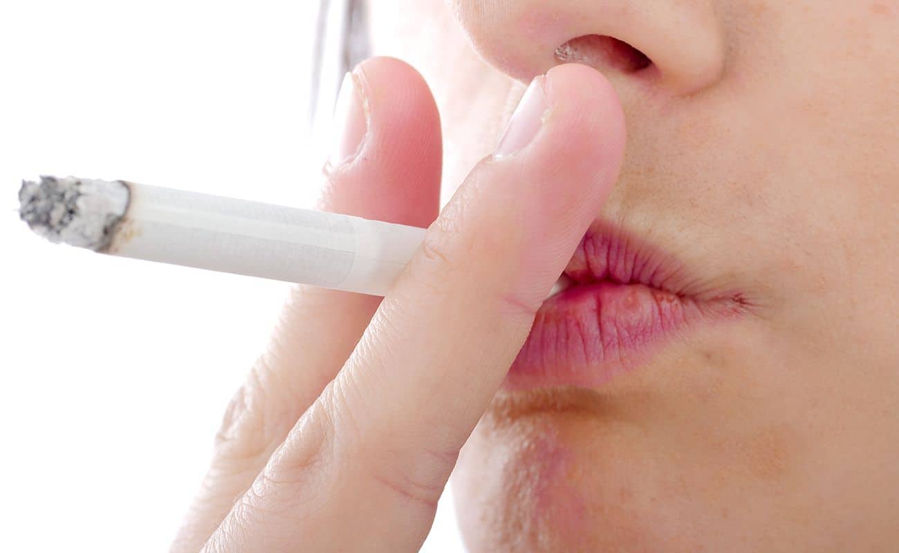 cigarro en boca de persona periodoncia e implantes monterrey